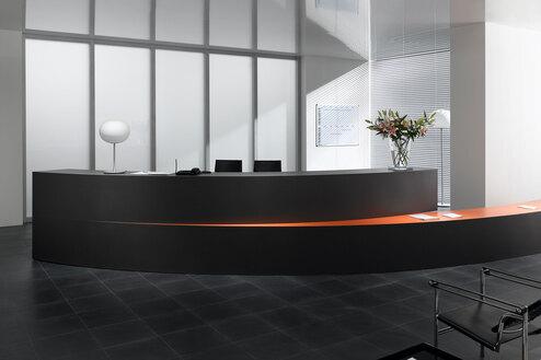 Hotelrezeption mit schwarz lackierter Empfangstheke und orangenem Kontrast