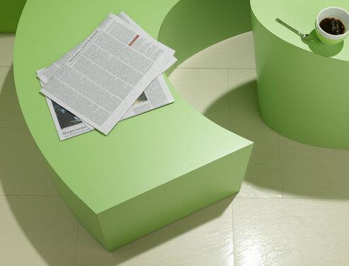 Detailaufnahme einer grünen Sitzbank mit Papierdokumenten und Tischausschnitt mit Kaffeetasse