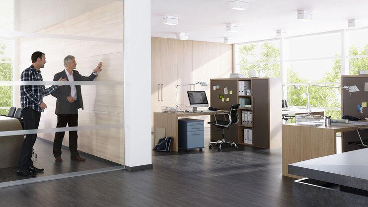 Impression eines Büros mit abgeschlossenem Raum mit Glaswand und offener Bürogestaltung.