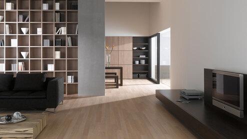 Offene Wohnraumimpression mit Einbauregal für Bücher und Dekoration in Trennwand mit hellem Holzboden