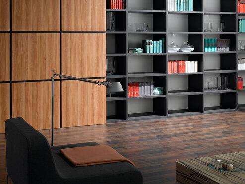 Detailaufnahme eines schwarz lackierten Bücherregals in Kombination mit quadratischen Holztüren für geschlossene Regalseite.